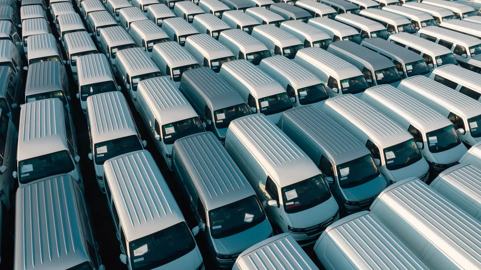 Rows of plain white cargo vans seen from above